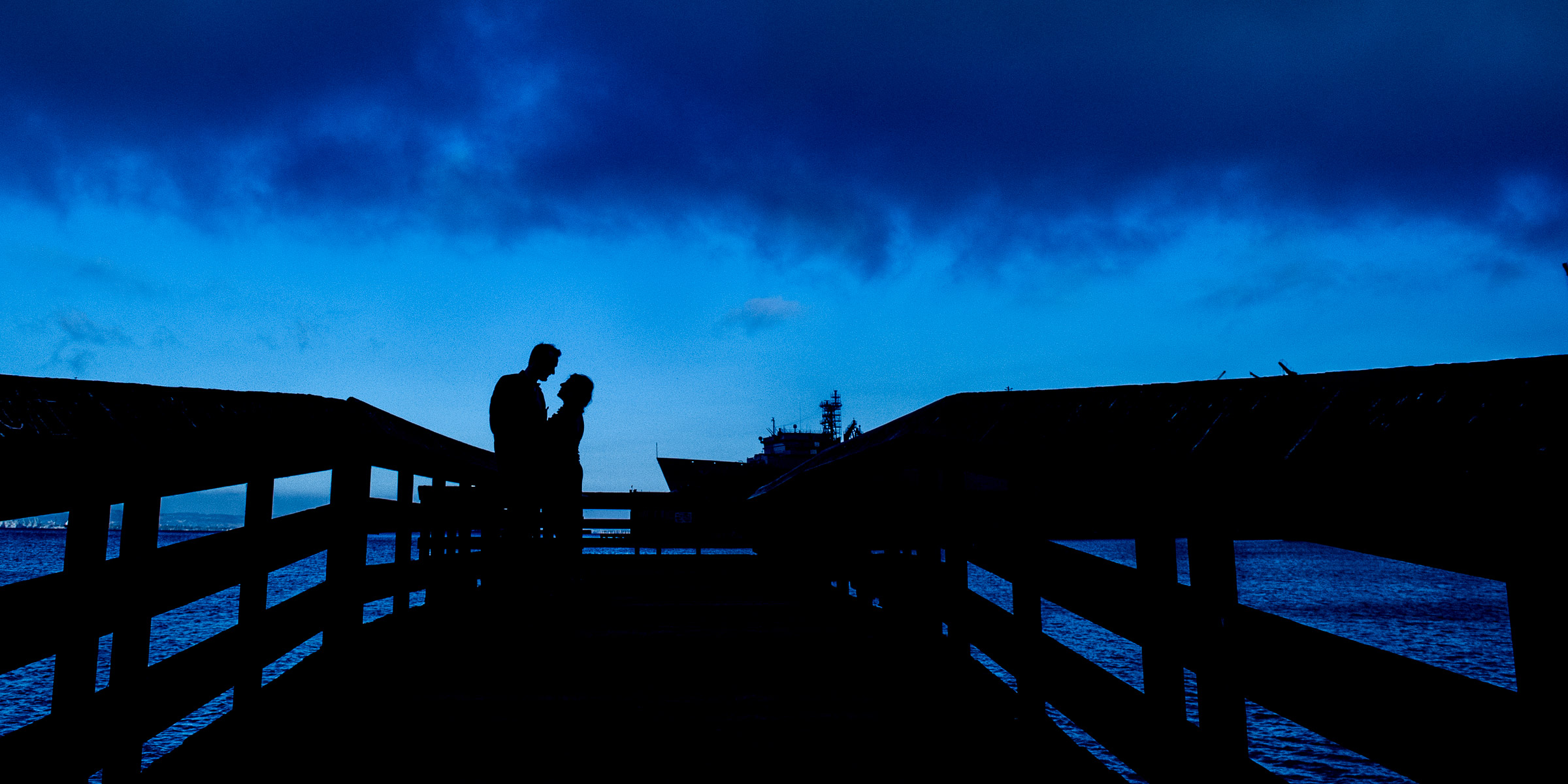 Engagement photo of man and woman silhouetted on a dock