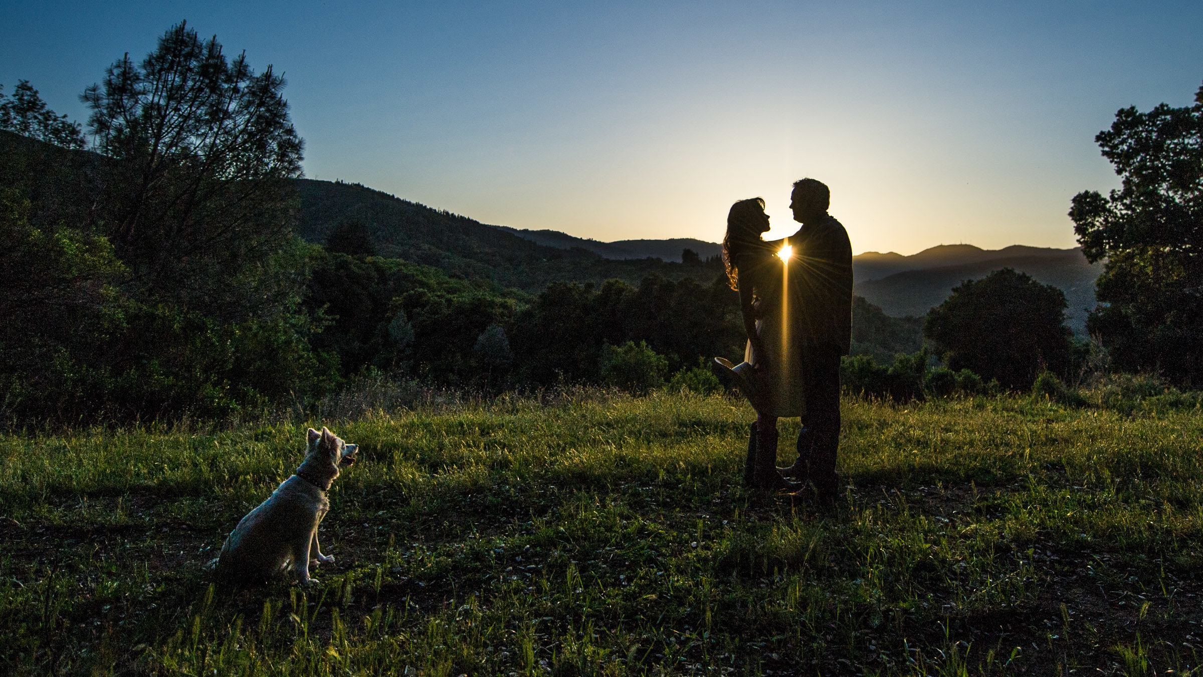 Cowgirl and boyfriend at sunset in the mountains with their dog.