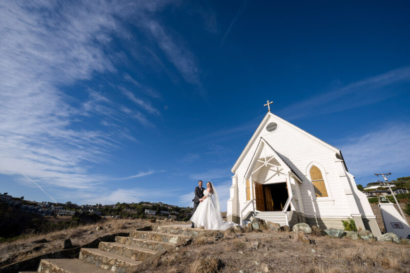 a bride and groom standing in front of a church.