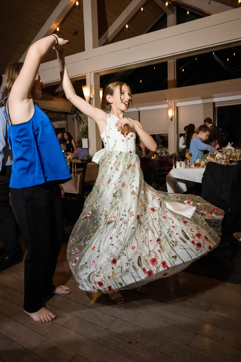 a girl in a white dress dancing with a woman in a blue jacket.