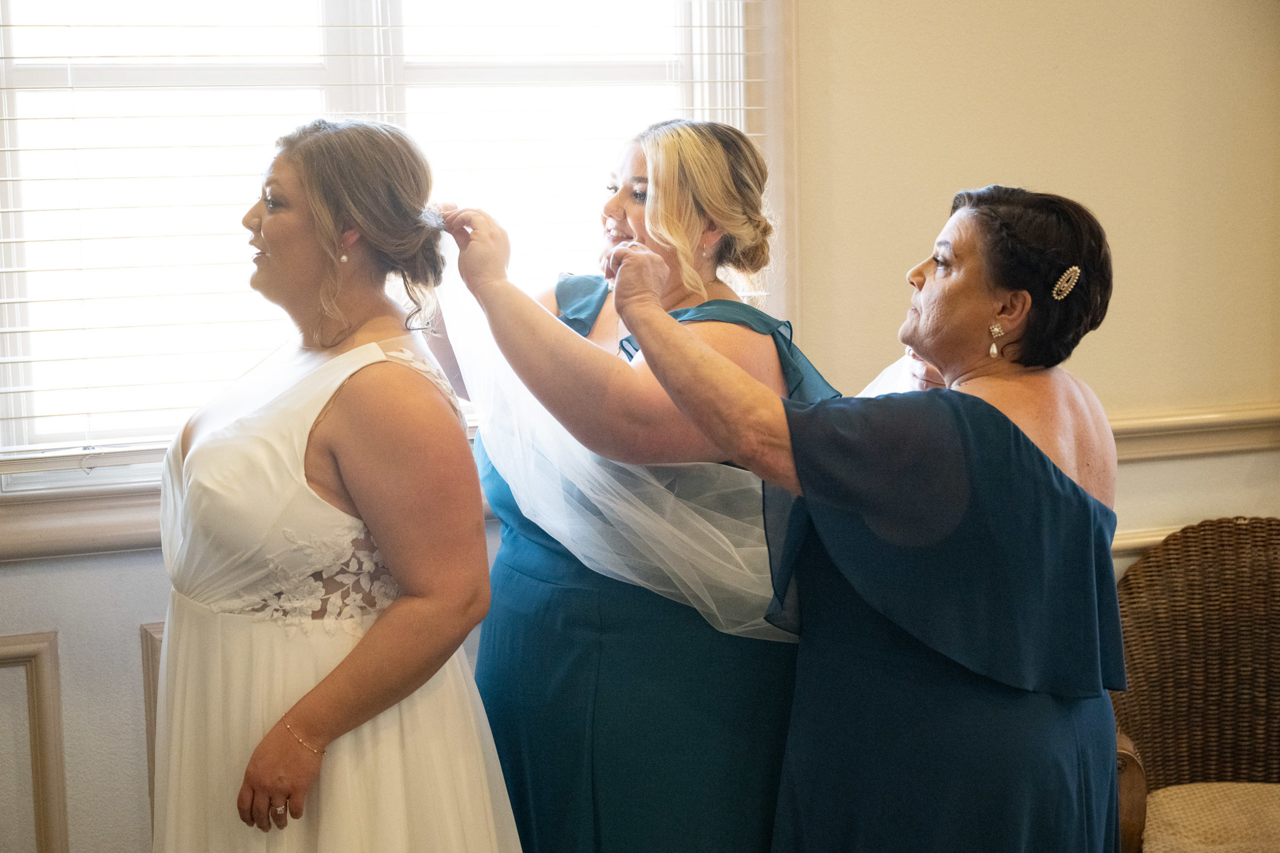 bride helped by mother and sister with veil
