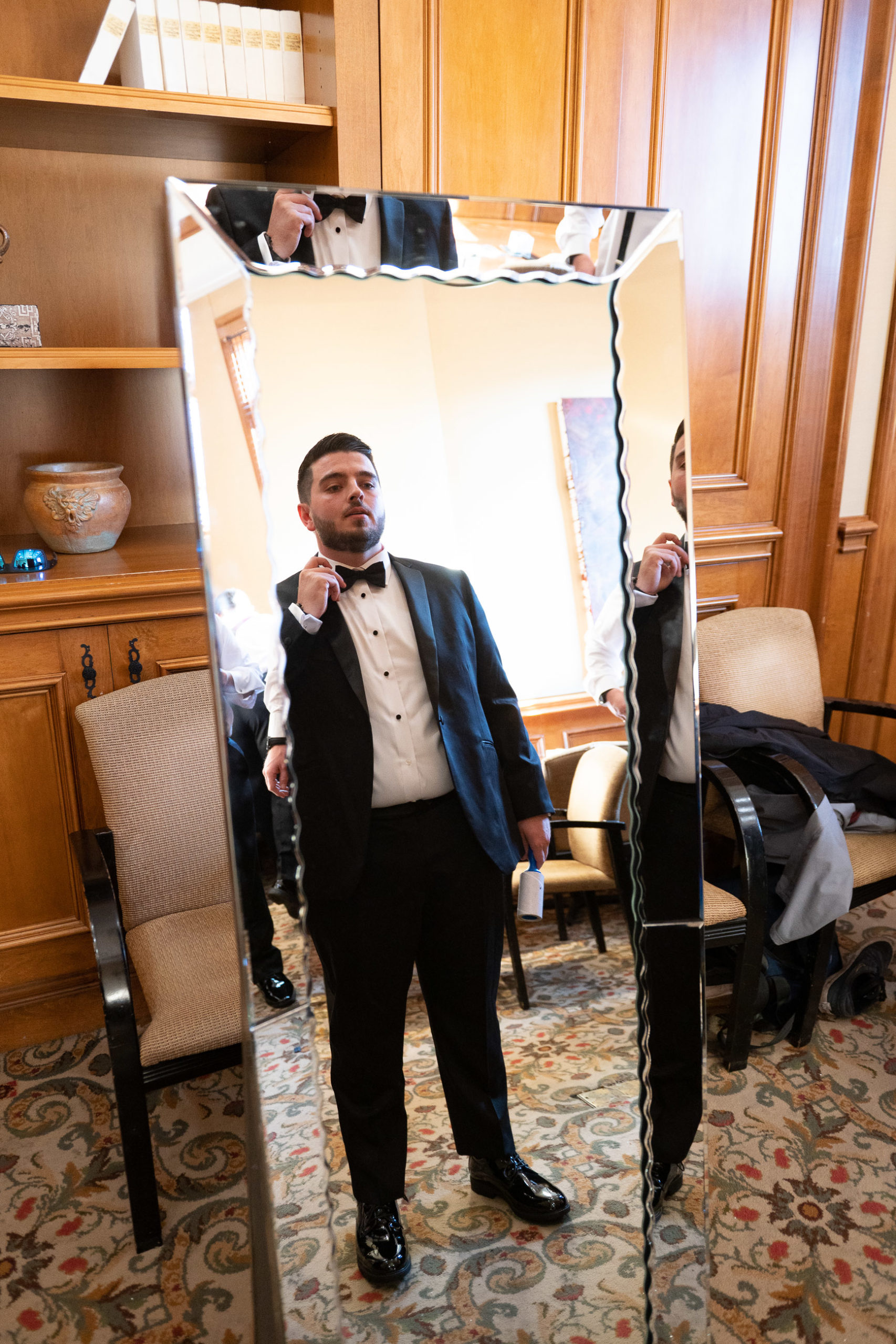 groom adjusting tie in mirror