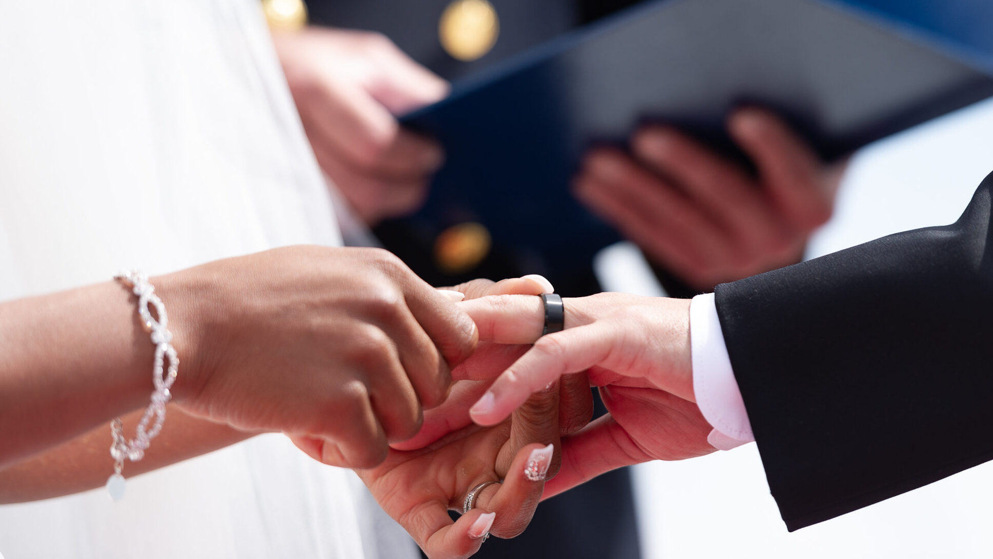 a close up of bride and groom exchanging rings