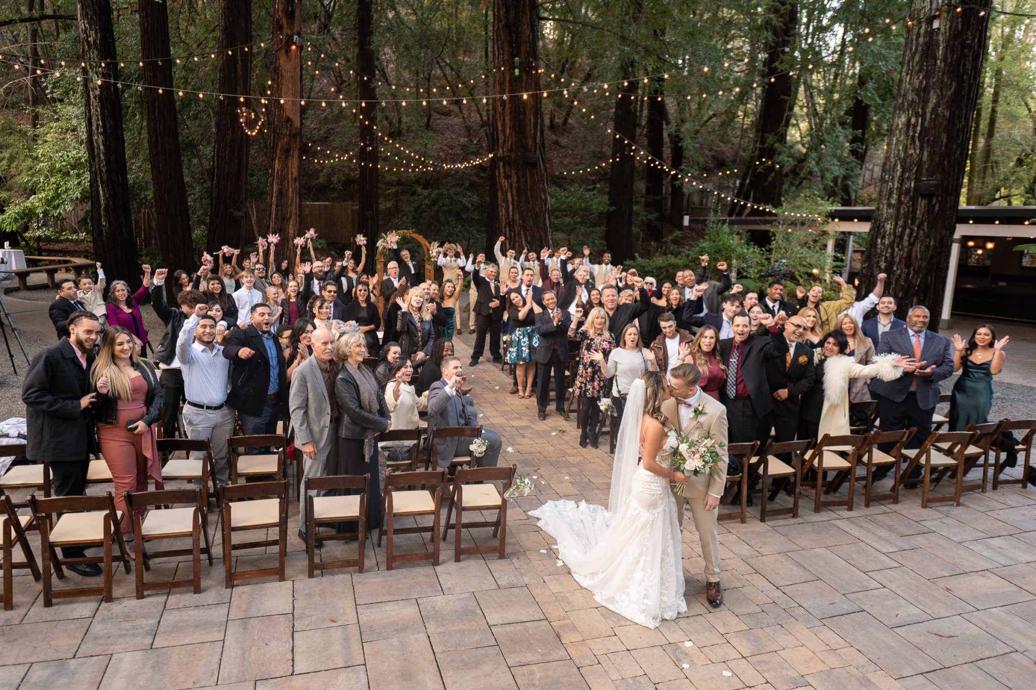 Wedding guests cheer behind newlyweds in the redwood grove at Deer Park Villa