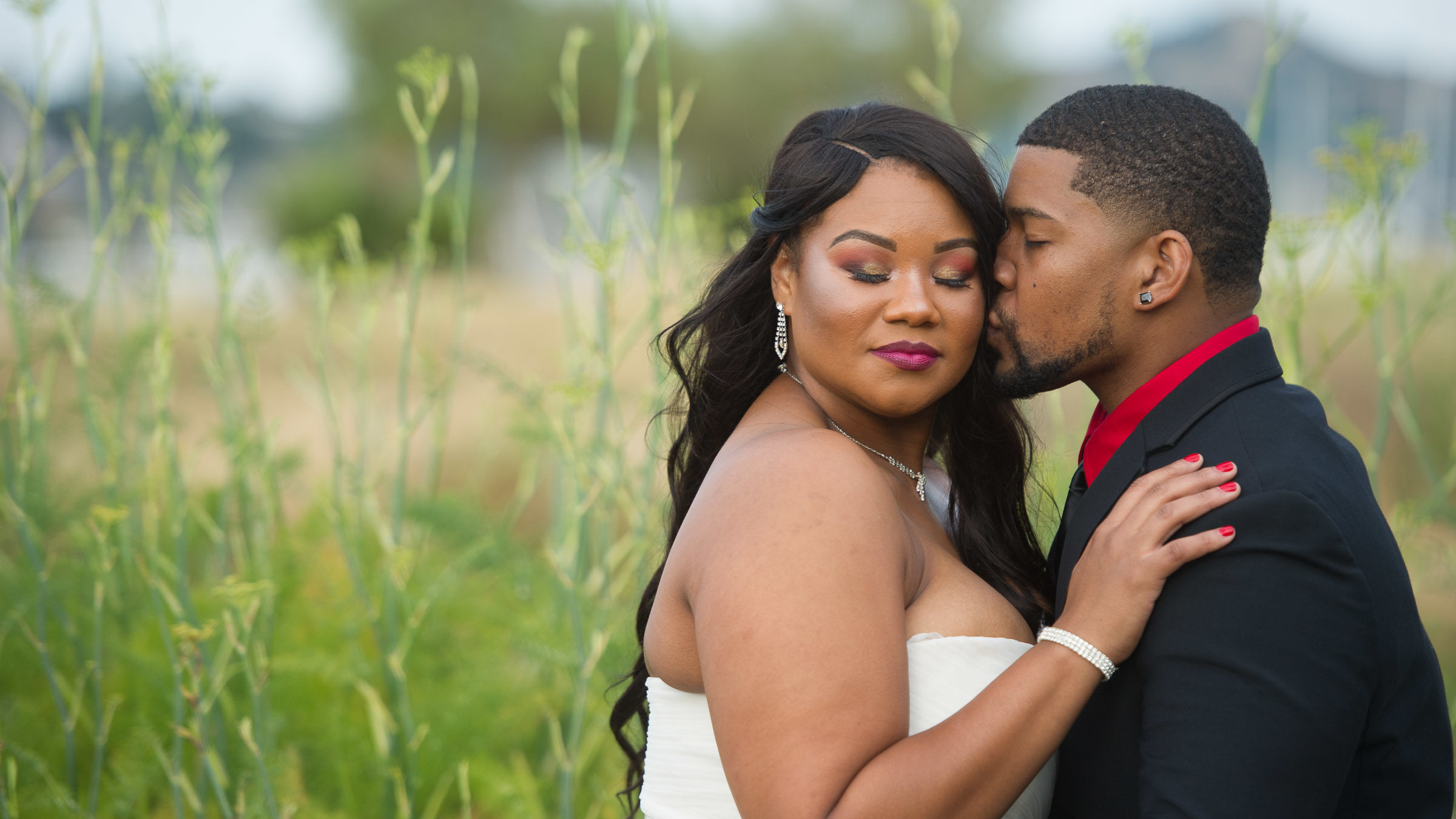 Bride and groom in embrace. Groom kissing bride's cheek.