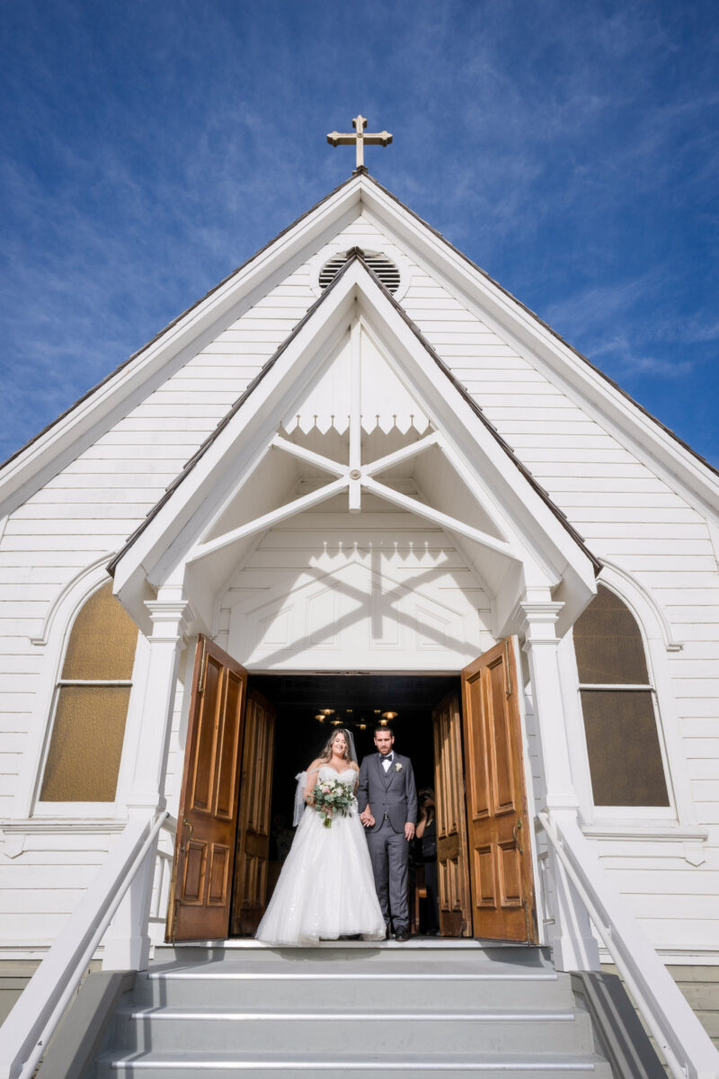 a bride and groom standing on the steps of a church.