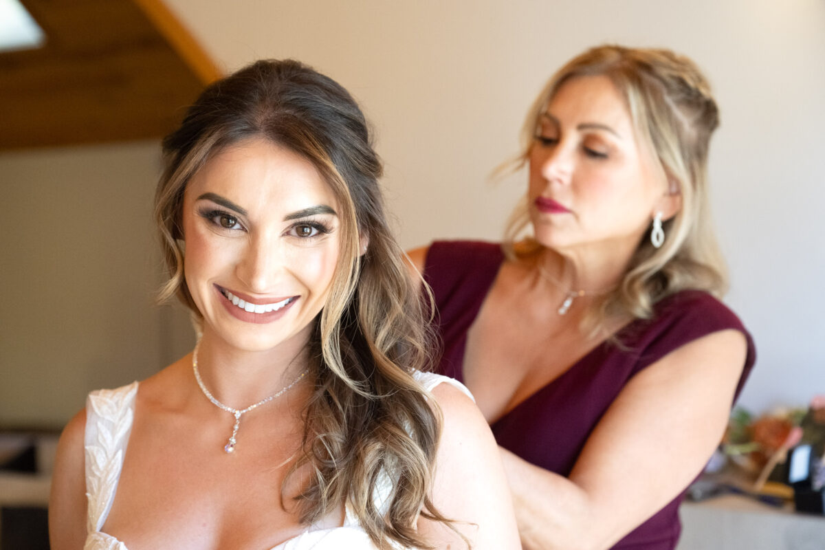 mother of bride putting necklace on bride