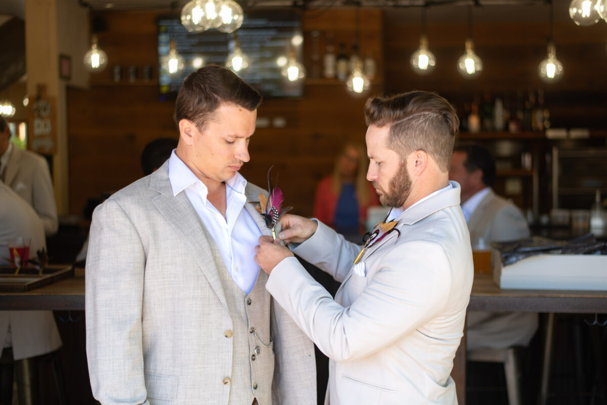 groomsman putting boutonniere on groom