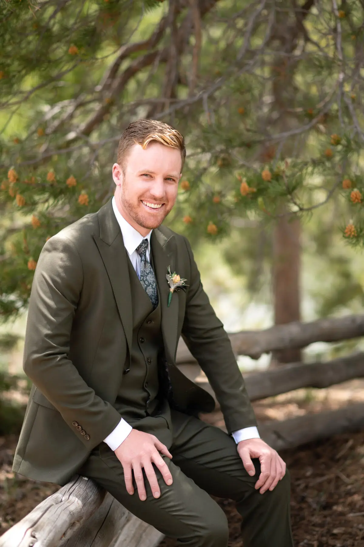 groom portrait sitting on fence in woods