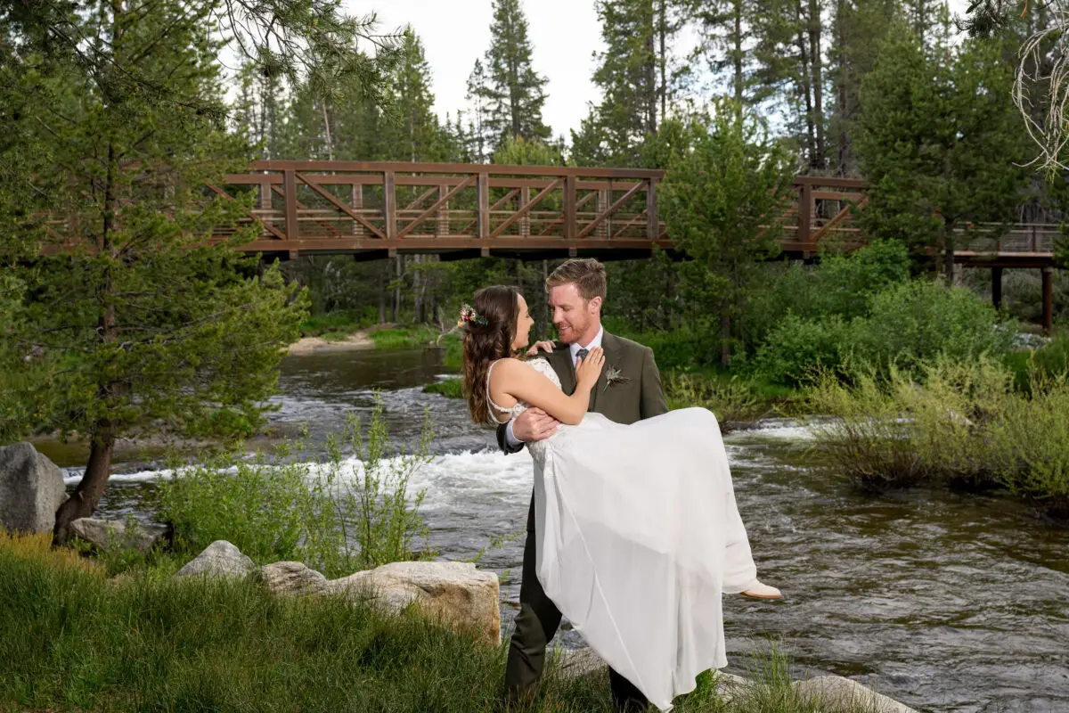 Bride and Groom portrait in woods holding bride next to mountain stream and bridge